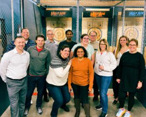 A large group of people posing for picture in an axe throwing bay